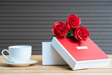 Red roses and gift box on wood background