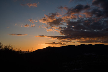 Dark dramatic clouds over mountain silhouette at sunset