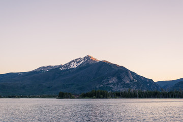 Lonely mountain lake with alpenglow on peaks after sunset in blue hour