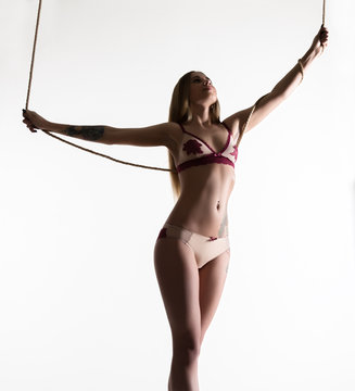 Perfect slim girl with a rope posing on a light background. Sexy athletic body.