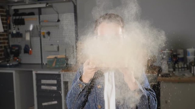 Close up of a boy in transparent glasses blowing away sawdust in slow motion. Kids in adult professions. hd