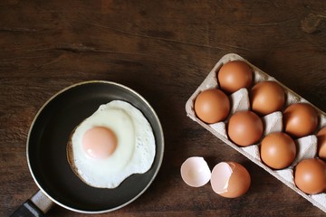 Eggs and fried egg on the wooden table.
