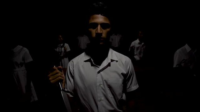 Boys and Girls with knives in their hand are standing in the poorly lit room then the light suddenly turn on.