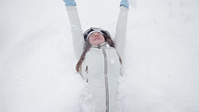 A young girl rejoices in winter and snow, plays in a winter park, does not lie in snow