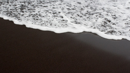 tidal waves on black sand beach