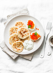 Gluten free rice flour pancakes and boiled eggs with red caviar - delicious breakfast, brunch on a light background, top view