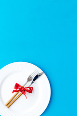 Dating on Valentine's day concept. Festive dishes, tableware on plate on blue background top view copy space