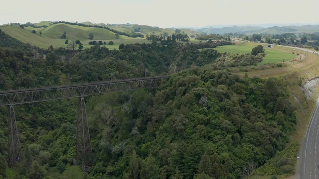 Aerial rise over Rangitikei ranges railway bridge with state highway one traveling up hill, New Zealand.