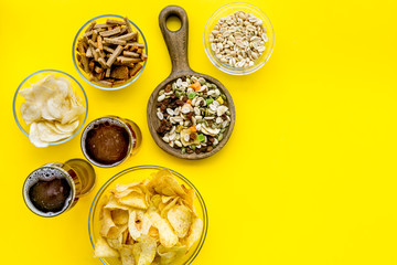 Fast food for TV watching. Snacks on desk.  Chips, nuts, rusks and beer on yellow background top...