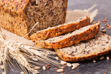 Loaf of wholegrain bread for breakfast, ingredients for baking and ears of rye or wheat grain - obrazy, fototapety, plakaty