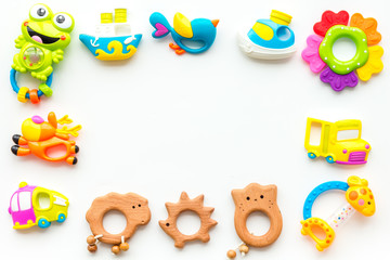 Handmade toys for newborn babies, plastic and wooden rattle on white background top view copy space frame