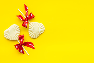 Obraz premium Heart-shaped lollipop for Valentine's day on yellow background top view space for text