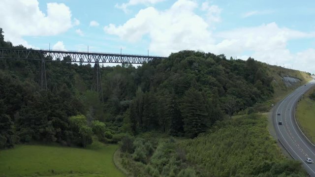 Aerial push shot, Rangitikei railway bridge with cars traveling on highway below, New Zealand.