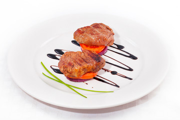 Dish of pork medallions on white background