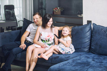 Obraz premium Family father, mother, daughter together beautiful and happy at home together on the couch watching telephoto