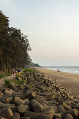 sea promenade and tsunami barrier against a sandy beach, green trees and the ocean