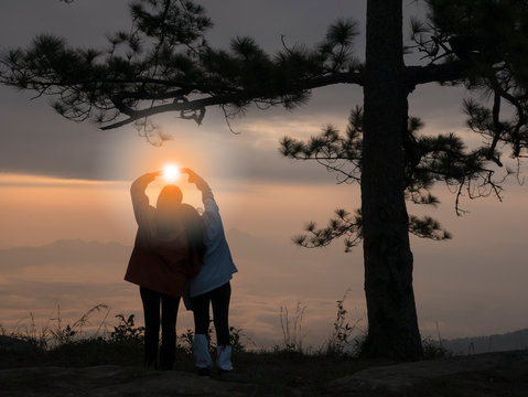 Girl shows love Beautiful view of Pha nok aen cliff in early morning sunrise. Very beautiful light and blue sky with sea of fog foreground. Phu kradueng national park