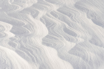 Fototapeta na wymiar Winding lines from the wind in the snow. Texture of crusty snow. Winter background.