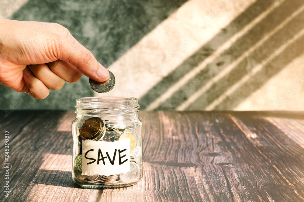 Wall mural save money, woman put coins in glass jar for money saving financial concept