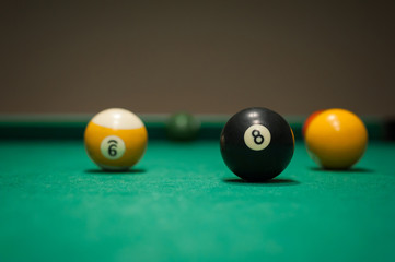 Sport billiard balls set arranged in shape of triangle on green billiard table in pub