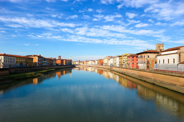 Fototapeta na wymiar Arno river and colorful houses around under the clear winter sky, Pisa, Tuscany, Italy