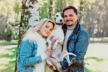 beautiful lovely couple (woman and man) in keans clothes walking with whippets dogs outdoor - healthy lifestyle