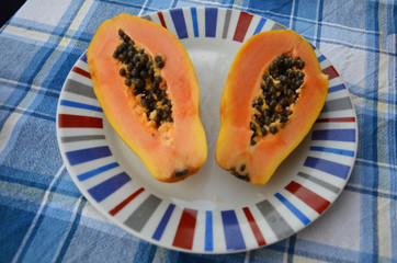 Papaya fruit on on the plate. Slices of sweet papaya on wooden background, Halved papayas with leaves,
