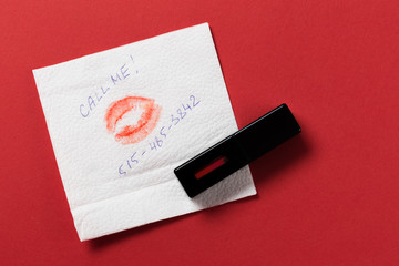 white paper napkin with lipstick and kiss on red background.