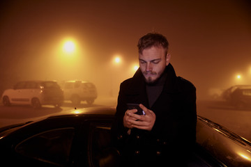 one young man, using smart-phone in dark night mist.