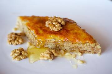 Close-up dessert is a piece of cake with walnuts, honey and pine nuts.