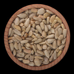 shelled seeds of sunflower in wooden cup isolated on black background. top view