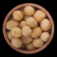 heap of hazelnuts in wooden cup isolated on black background. top view