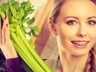 Naklejka premium Woman in kitchen holds green celery
