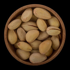 heap of Pistachio in wooden cup isolated on black background. top view