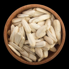 heap of white seeeds of sunflower in wooden cup isolated on black background. top view