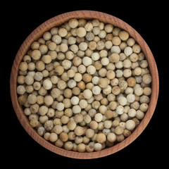 seeds of white pepper in wooden cup isolated on black background. top view