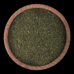 Obraz na płótnie Canvas dried ground dill in wooden cup isolated on black background. top view