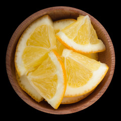 slices of lemon in wooden cup isolated on black background. top view