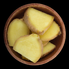 slices of ginger  in wooden cup  isolated on black background. top view