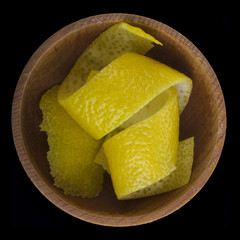 rind of lemon  in wooden cup isolated on black background. top view