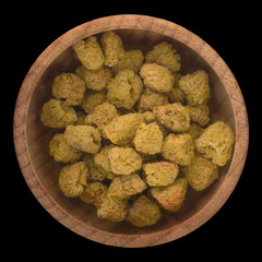 dried yellow raspberries in wooden cup isolated on black background. top view