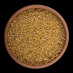 seeds of yellow mustard  in wooden cup isolated on black background. top view