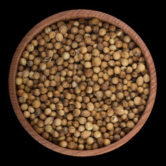 coriander seeds  in wooden cup isolated on black background. top view