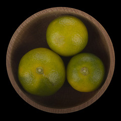  heap of limequates  in wooden cup isolated on black background. top view