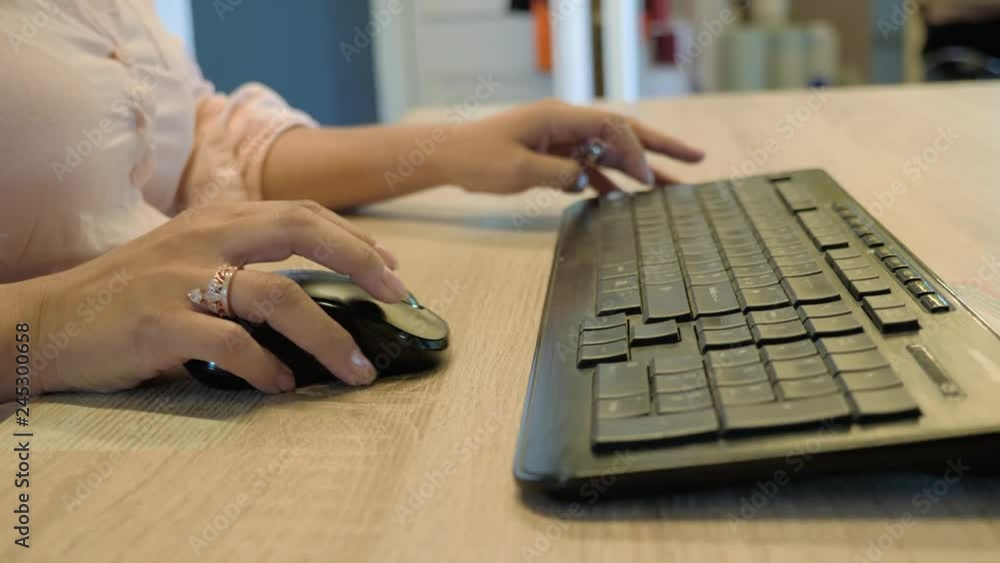 Poster close up on a woman office worker using a mouse and keyboard to run her computer and perform her job