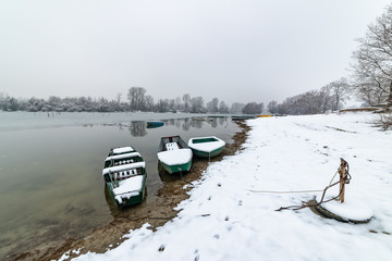 Naklejka premium Danube island (Šodroš) near Novi Sad, Serbia. Colorful landscape with snowy trees, beautiful frozen river. A boats covered with snow or submerged