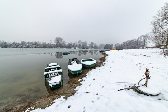 Danube island (&Scaron;odro&scaron;) near Novi Sad, Serbia. Colorful landscape with snowy trees, beautiful frozen river. A boats covered with snow or submerged