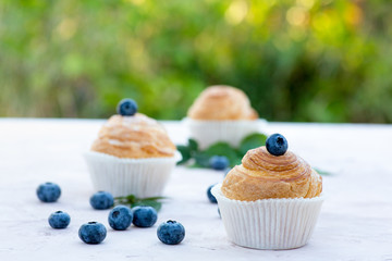 Fresh baked golden muffins with blue berries on rustic wooden background shot in natural light