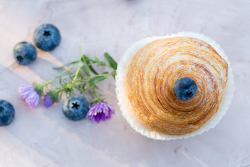 Fresh baked golden muffins with blue berries on rustic wooden background shot in natural light