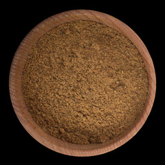 ground nutmeg (nutmeg powder)  in wooden cup isolated on black background. top view